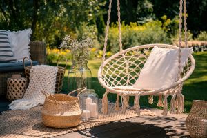 jardin avec fauteuil suspendu en bois et décorations dans les tons blancs