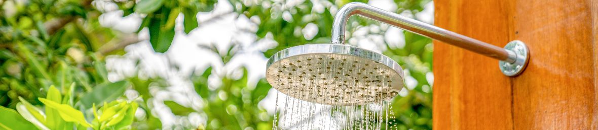 pommeau de douche en acier sur un plateau en bois dans un jardin